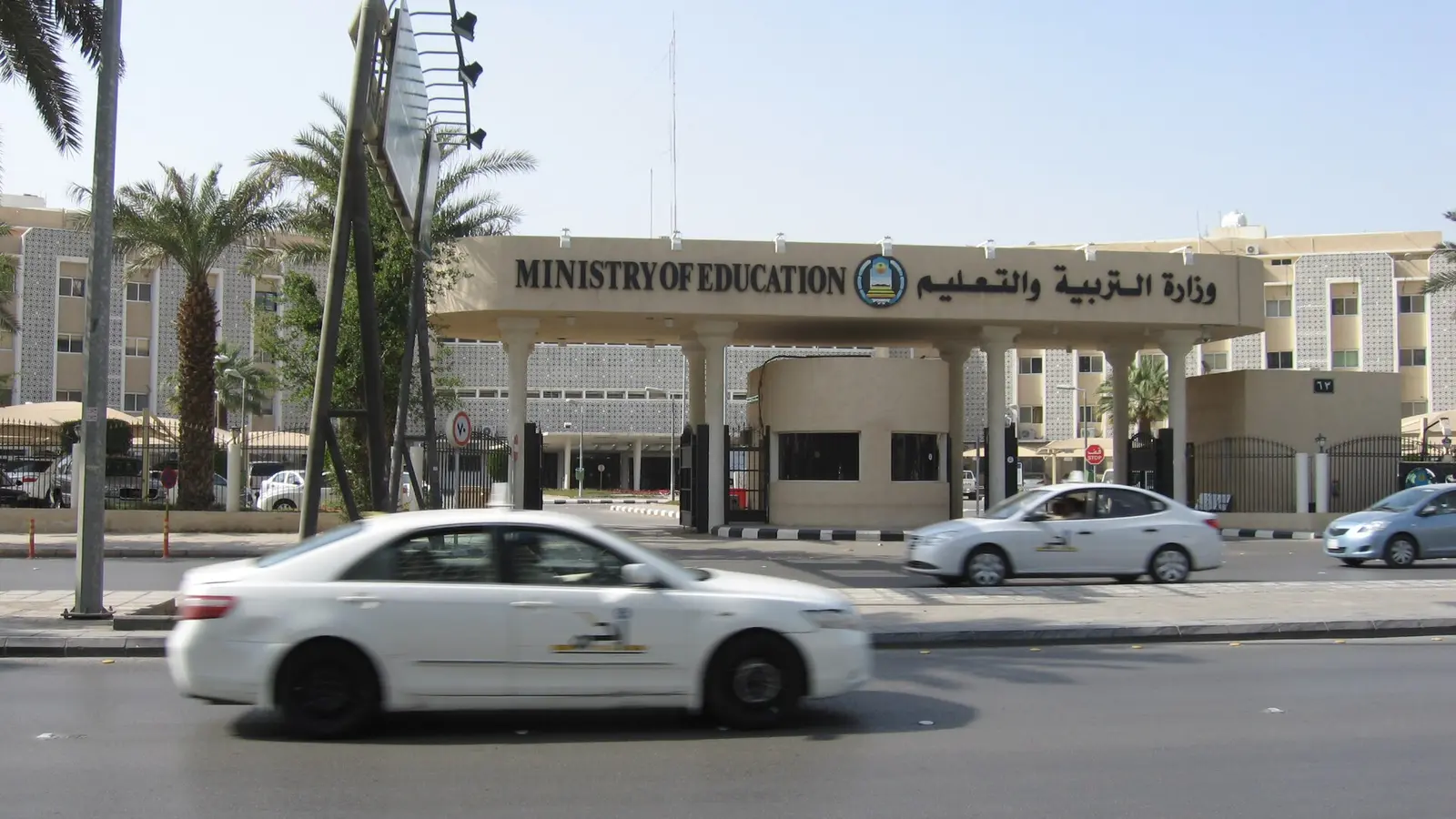 واجهة مبنى وزاري حكومي سعودي بلافتتين عربية وإنجليزية، وسيارات تعبر الشارع أمامه