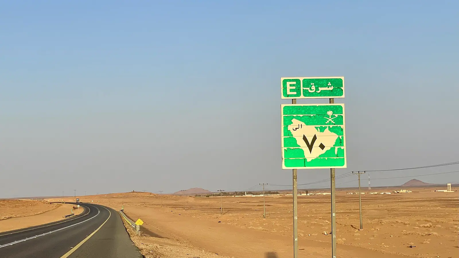 طريق صحراوي ممتد ولافتة إرشادية خضراء لرقم الطريق واتجاه شرق، بلا أي مبنى حكومي محدد