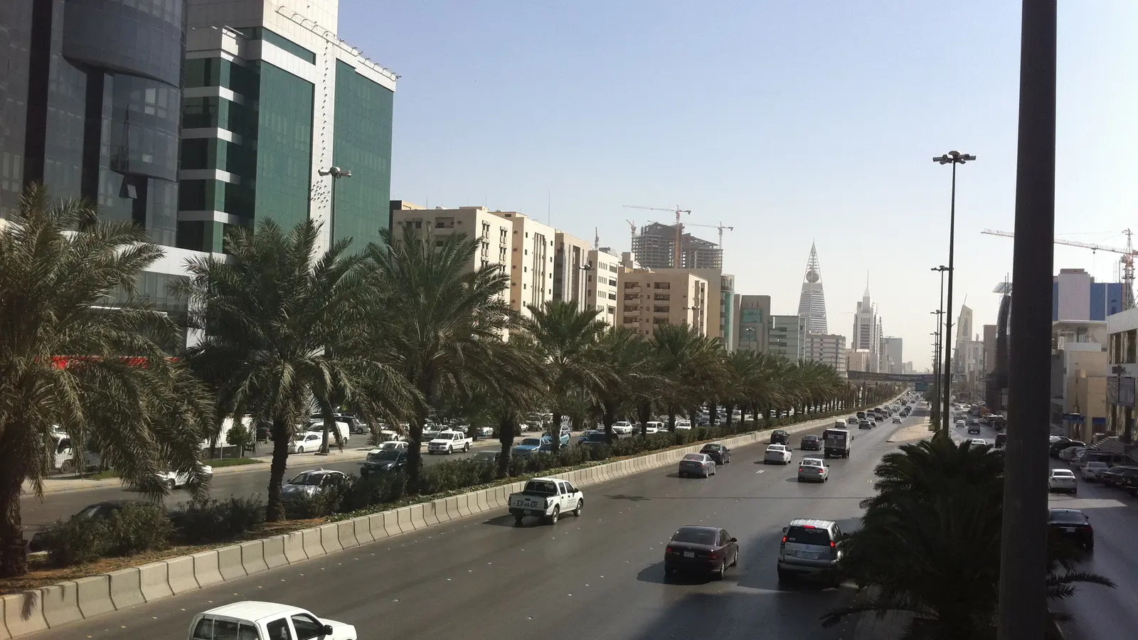 طريق الملك فهد في الرياض وحركة المركبات بين صفوف النخيل وأبراج المدينة، مشهد الطريق اليومي للسائق الخاص الذي تتراكم على سجله المخالفات المرورية قبل موعد تجديد الإقامة
