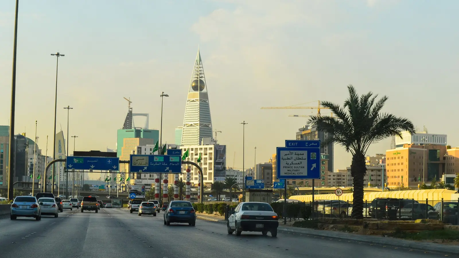 حركة المركبات على طريق الملك فهد في مدينة الرياض مع اللوحات الإرشادية وأبراج المدينة في الأفق