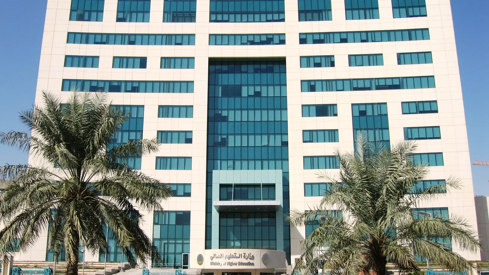 واجهة مبنى حكومي وزاري في الرياض بمدخله الزجاجي وأشجار النخيل المحيطة به، يمثّل الطابع الإداري الذي تُنجَز عليه معاملات العمالة والعقود الحكومية