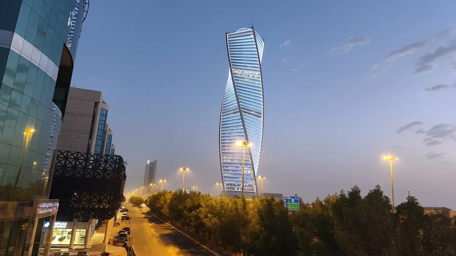 برج مجدول الملتوي في الرياض عند الغسق وسط واجهات زجاجية لمبانٍ تجارية، مشهد يمثل بيئة الشركات والسجلات التجارية في السعودية