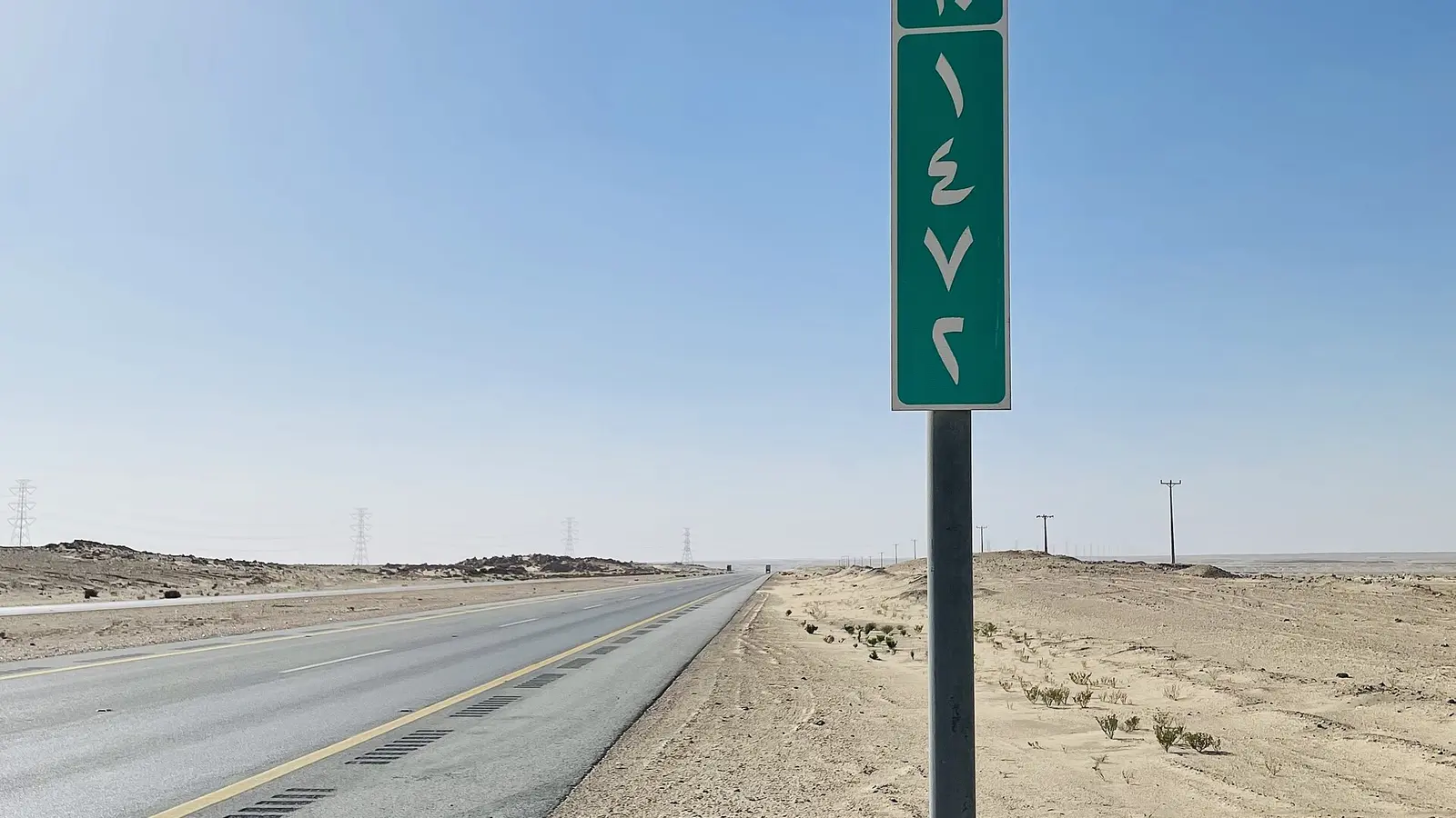 طريق سريع باتجاه الرياض في الصحراء مع لوحة إرشادية خضراء تحمل رقم الطريق ومسافته
