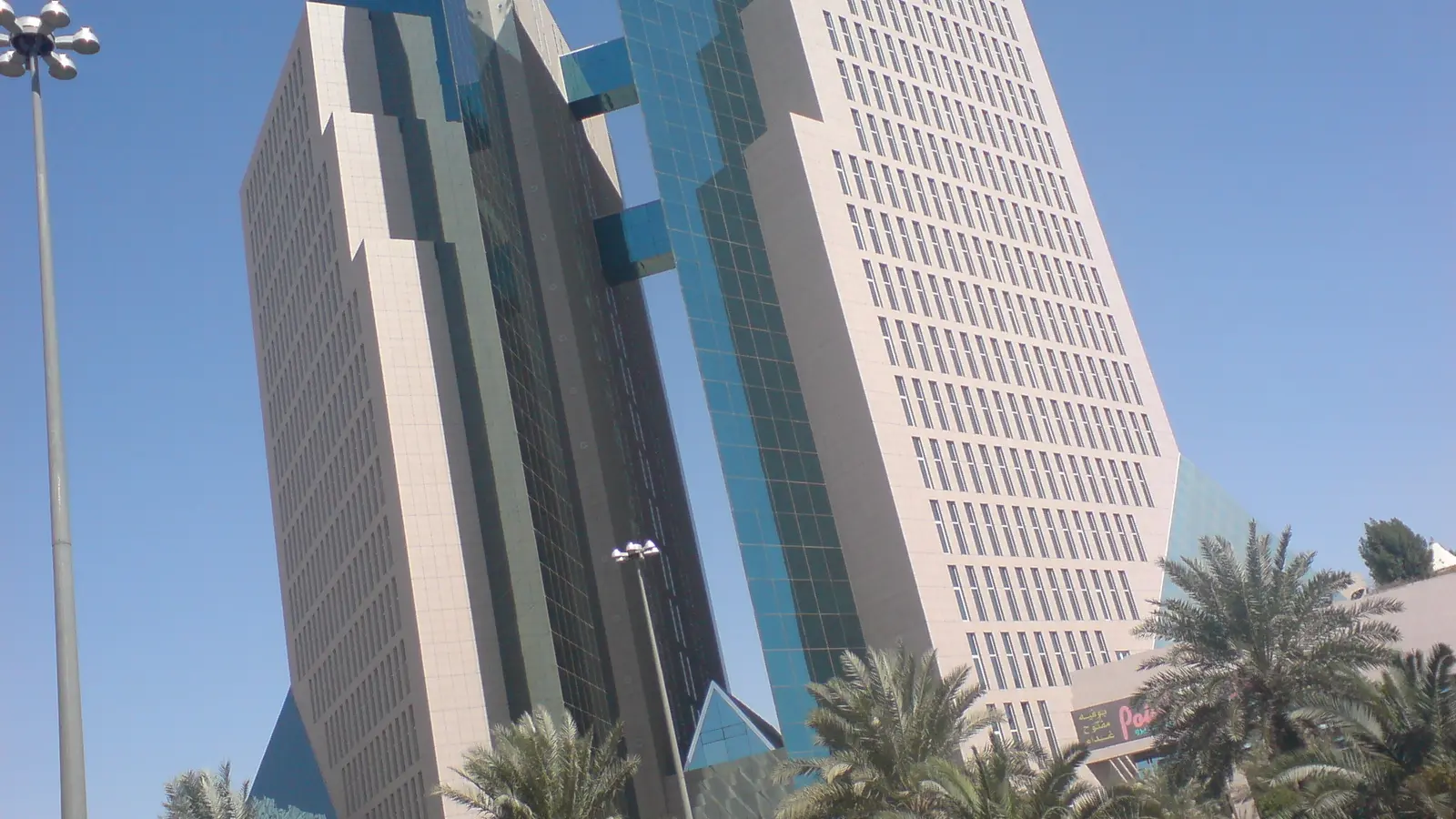 برج مكاتب تجارية حديث في الرياض بواجهات زجاجية ونخيل أمامه