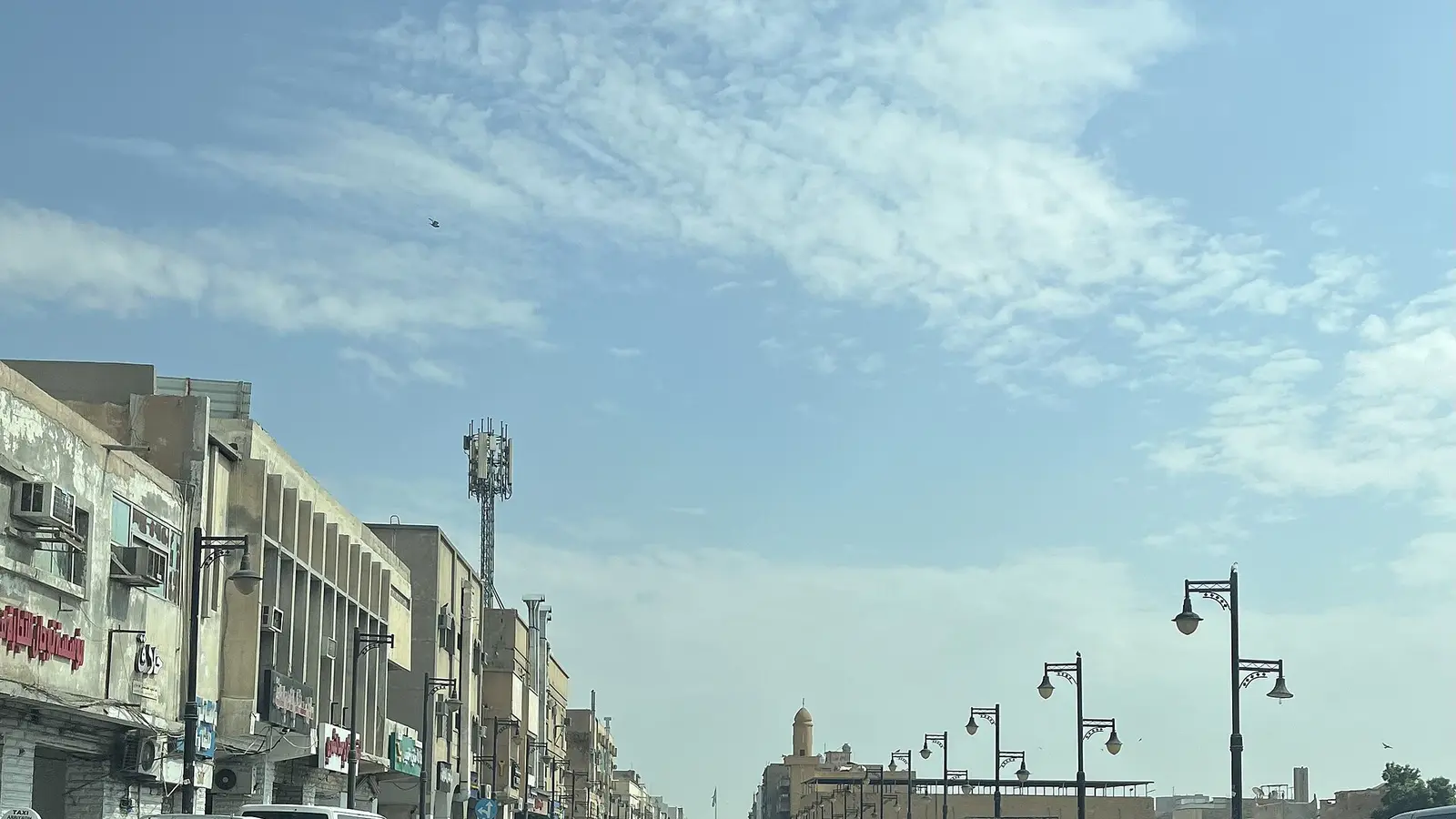 منظر عام لشارع تجاري في حي الشميسي بالرياض تظهر فيه واجهات المحلات ولوحاتها والمركبات المصطفة على الجانبين