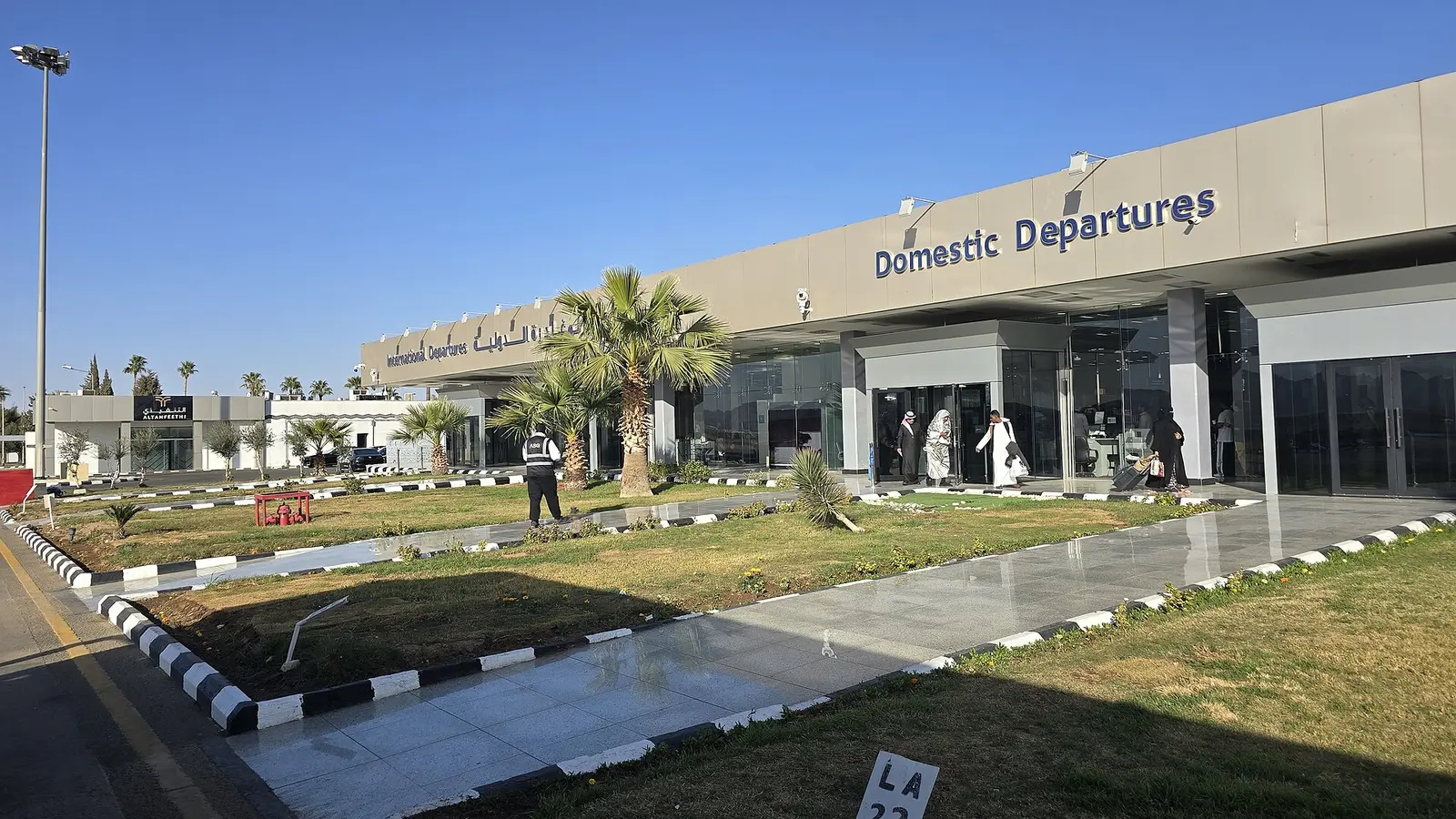 واجهة صالة المغادرات في مطار حائل الدولي، مع مسافرين أمام مدخل الصالة
