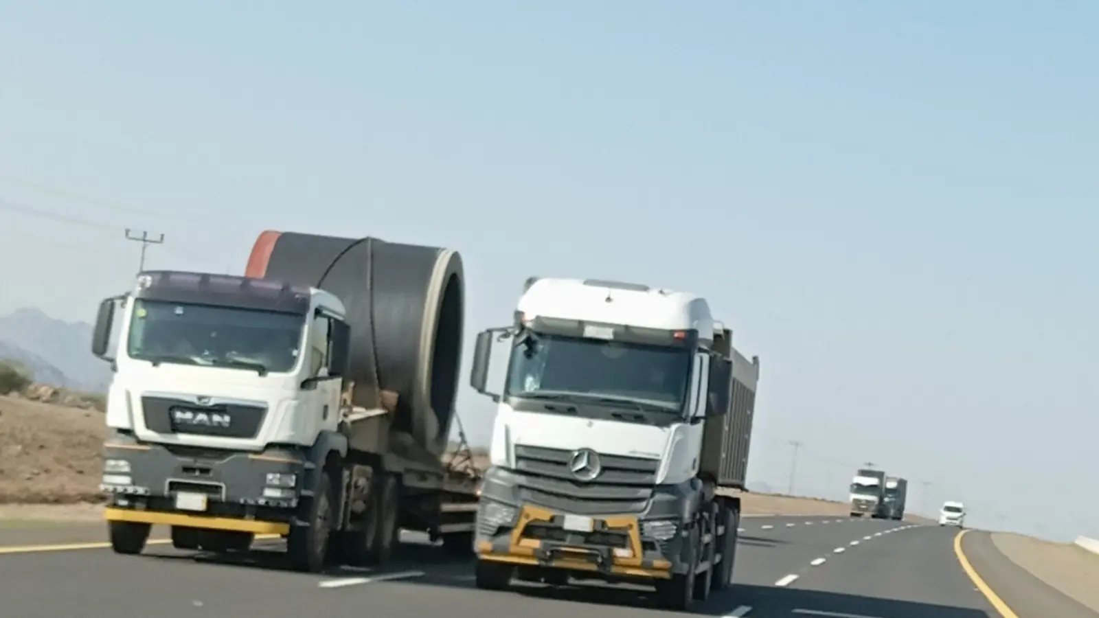 شاحنتا نقل ثقيل على طريق سريع في السعودية، إحداهما تحمل حمولة أسطوانية ضخمة غير قابلة للتجزئة