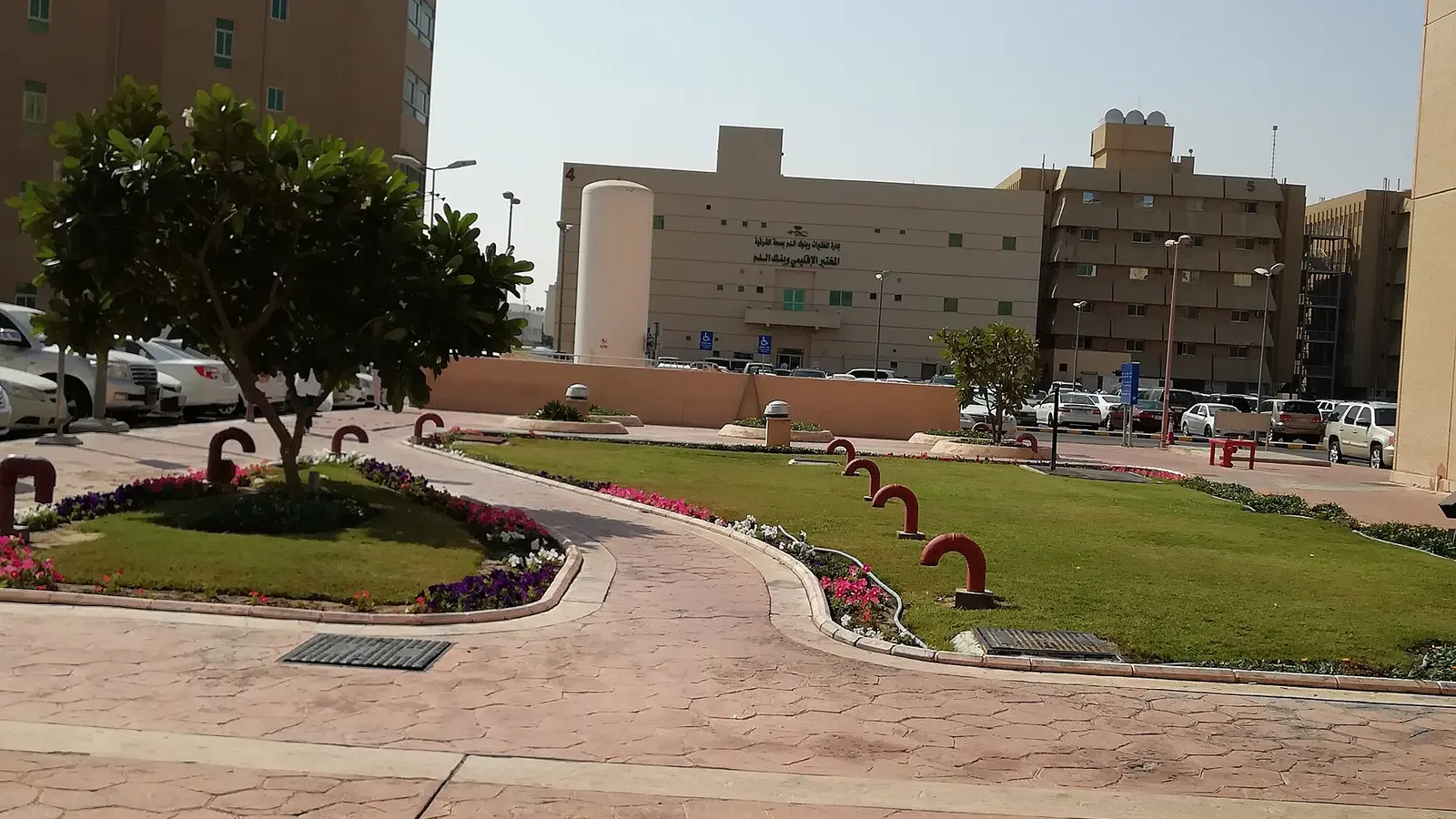 واجهة مستشفى حكومي سعودي بالدمام مع ساحة داخلية مشجّرة