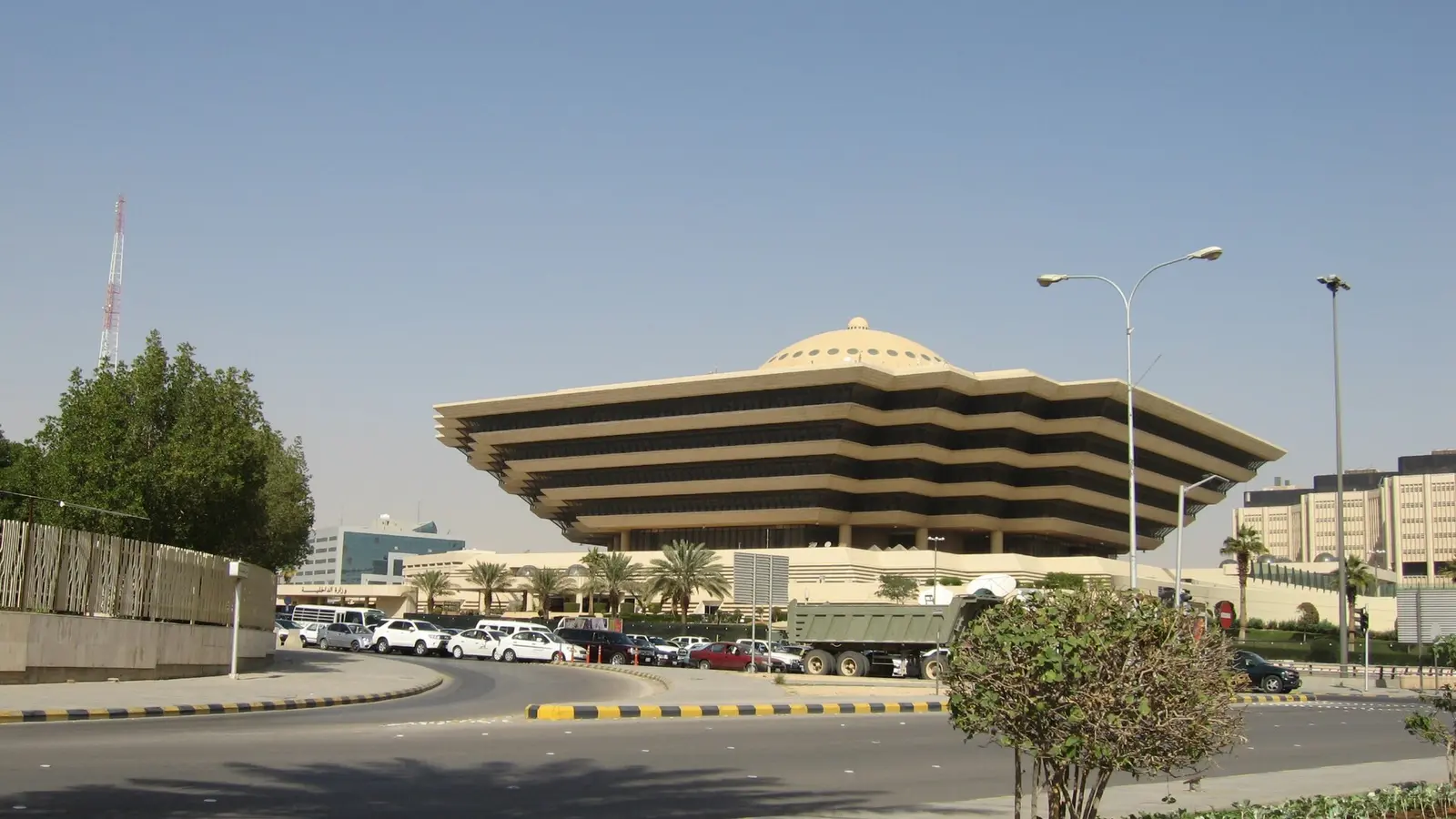 واجهة مبنى وزارة الداخلية السعودية في الرياض نهارًا، ويظهر أمامه طريق دائري وسيارات متحركة