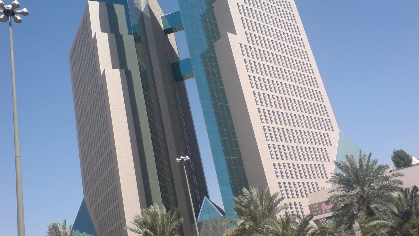 واجهة مبنى تجاري حديث متعدد الطوابق في مدينة الرياض بواجهات زجاجية ونخيل أمامه